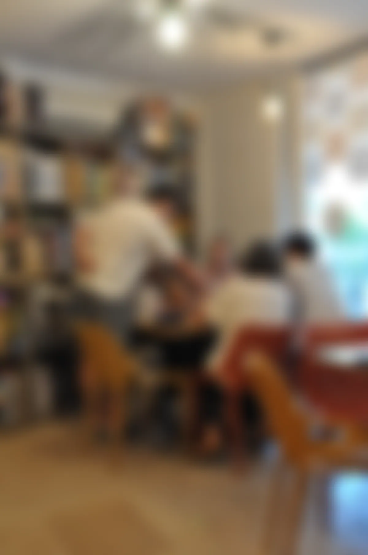Joueurs attablés dans la salle du bar à jeux La Luciole, devant les étagères de jeux